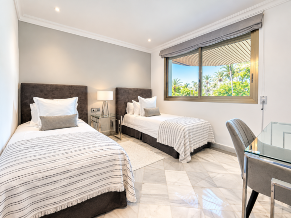Dormitorio moderno con dos camas y vistas tropicales