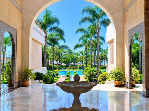 Entrada monumental con jardín tropical y piscina